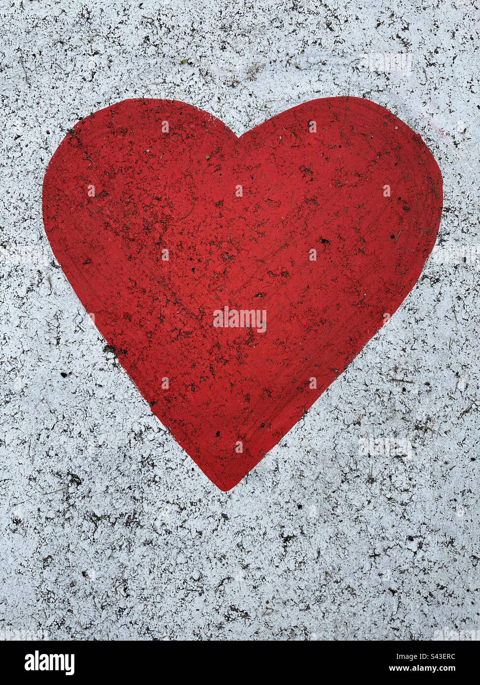Red heart shaped paint on pavement with white textured background. - Smartphone Captured Stock Image