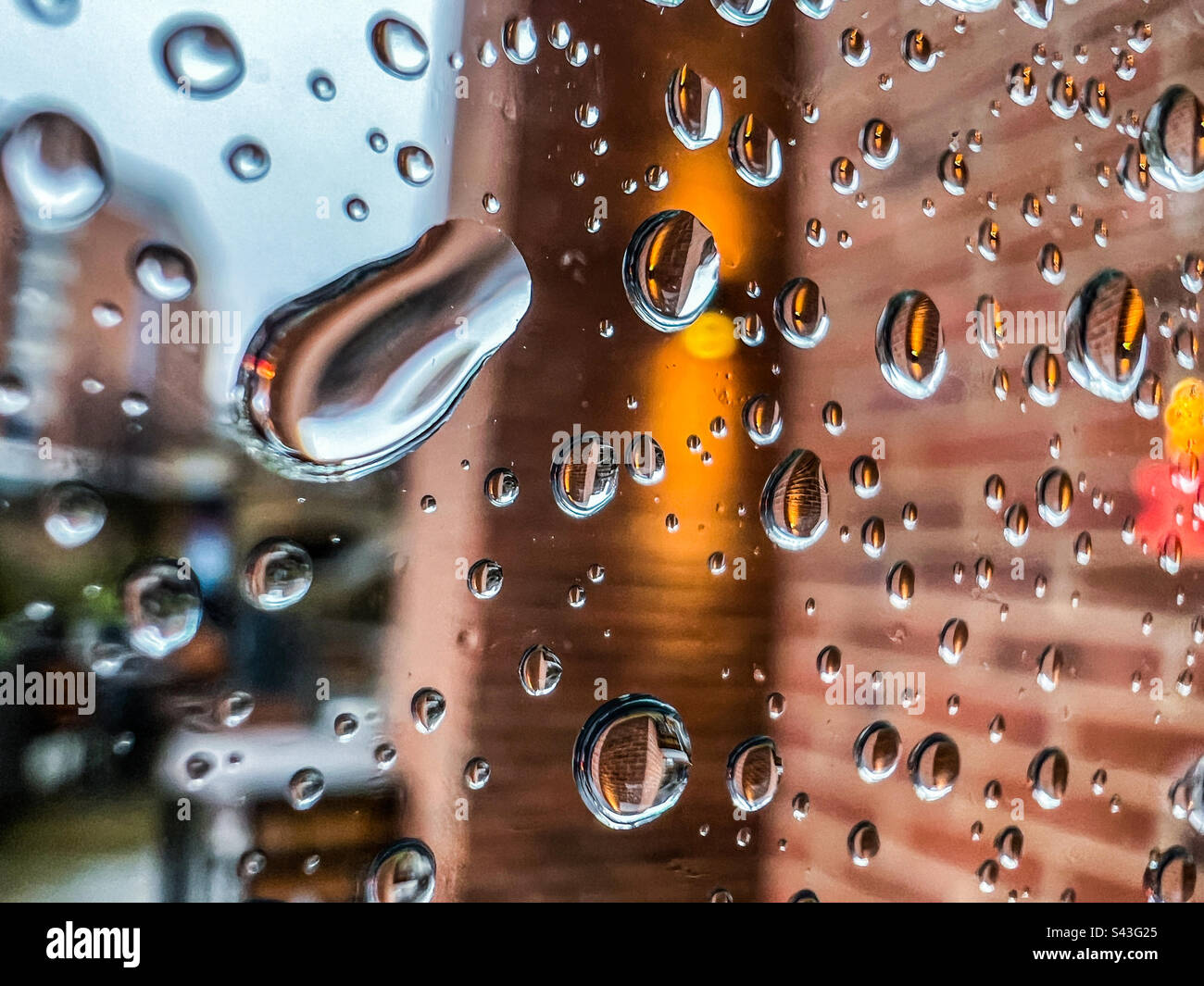 Raindrops on glass window in city - Smartphone Captured Stock Image