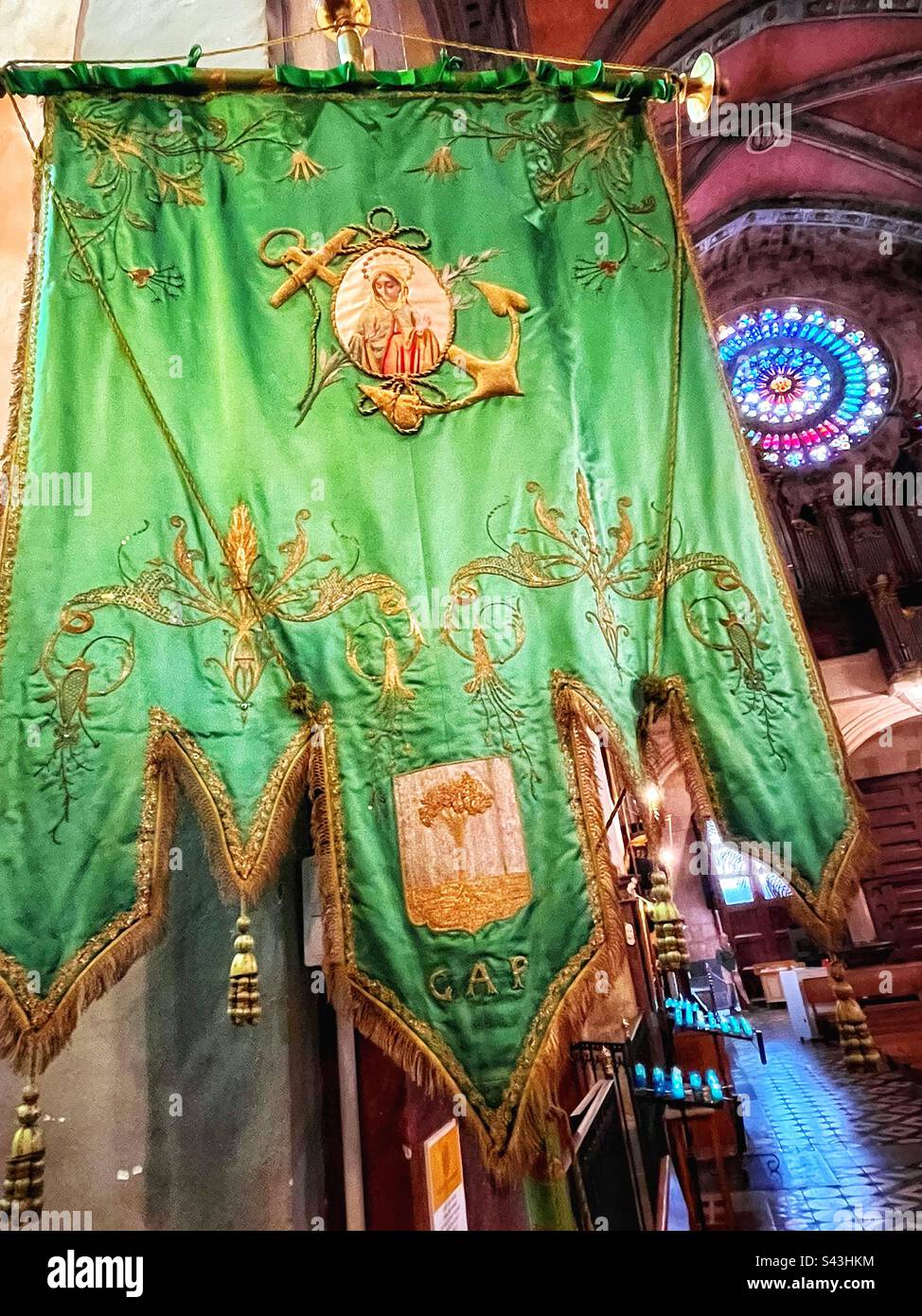 Green flag or pennant with anchor in the Church of St Bartholomew in Soller. The village is connected to the port and fishing. Rose window in background. Stock Photo