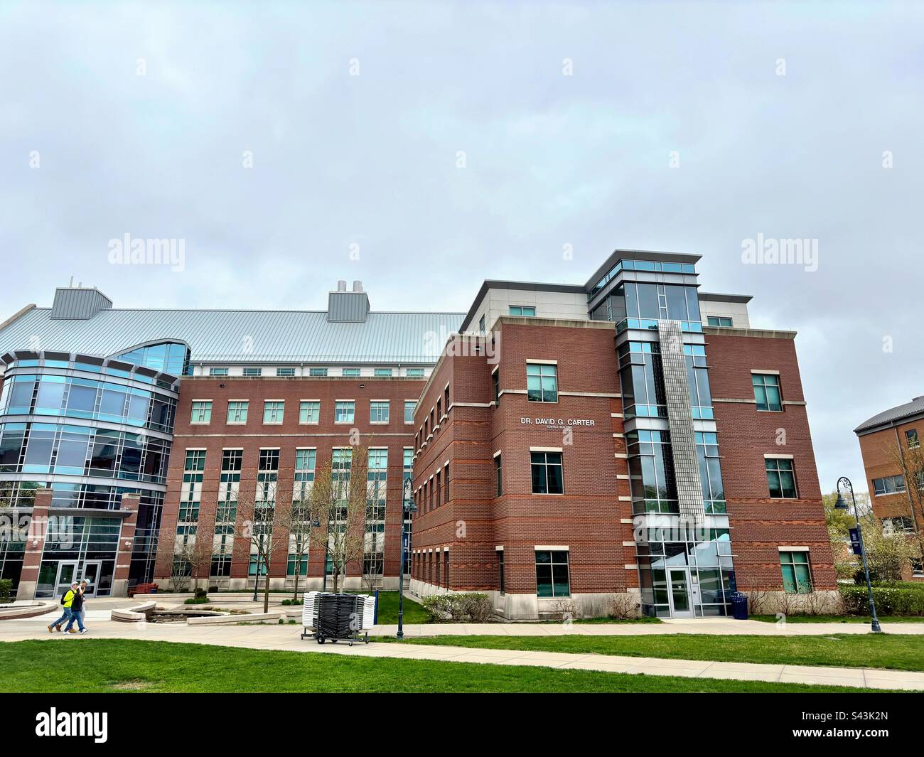 Willimantic, Connecticut, USA: exterior of science building at Eastern Connecticut State University. Campus on a cloudy day with 3 students walking. - Smartphone Captured Stock Image