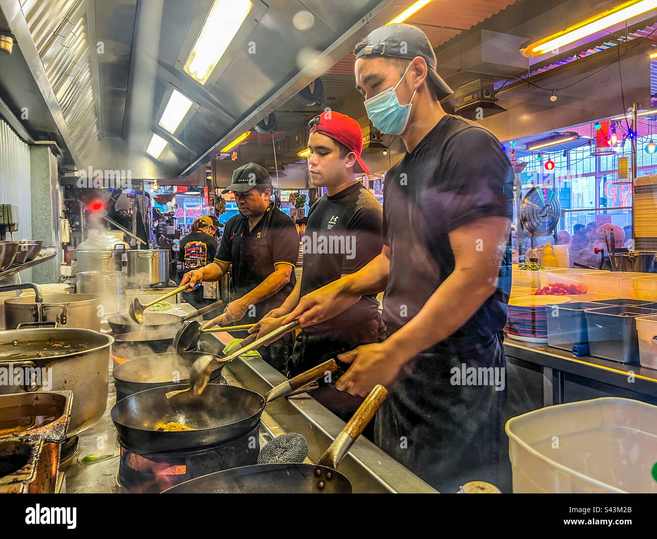 Chefs preparing Chinese food in woks in restaurant Stock Photo Alamy