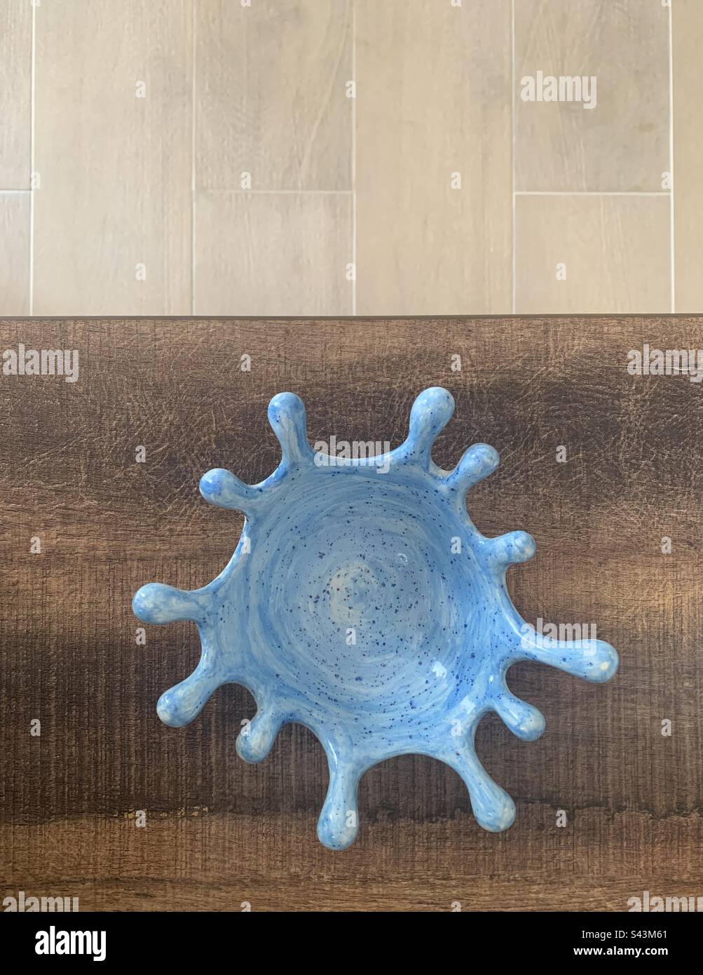 Closeup image of a hand painted blue and white speckled ceramic bowl against a wooden background Stock Photo