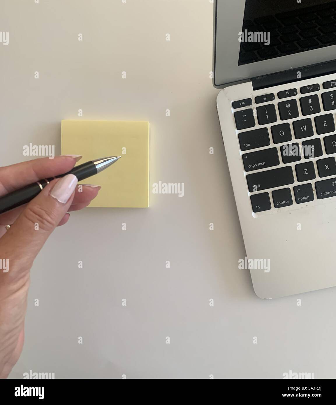 Woman with a pen in her hand making notes next to her portable computer - Smartphone Captured Stock Image