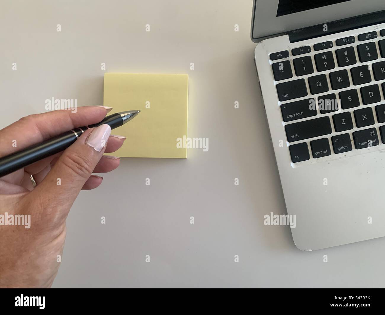 Woman with a pen in her hand making notes next to her portable computer - Smartphone Captured Stock Image