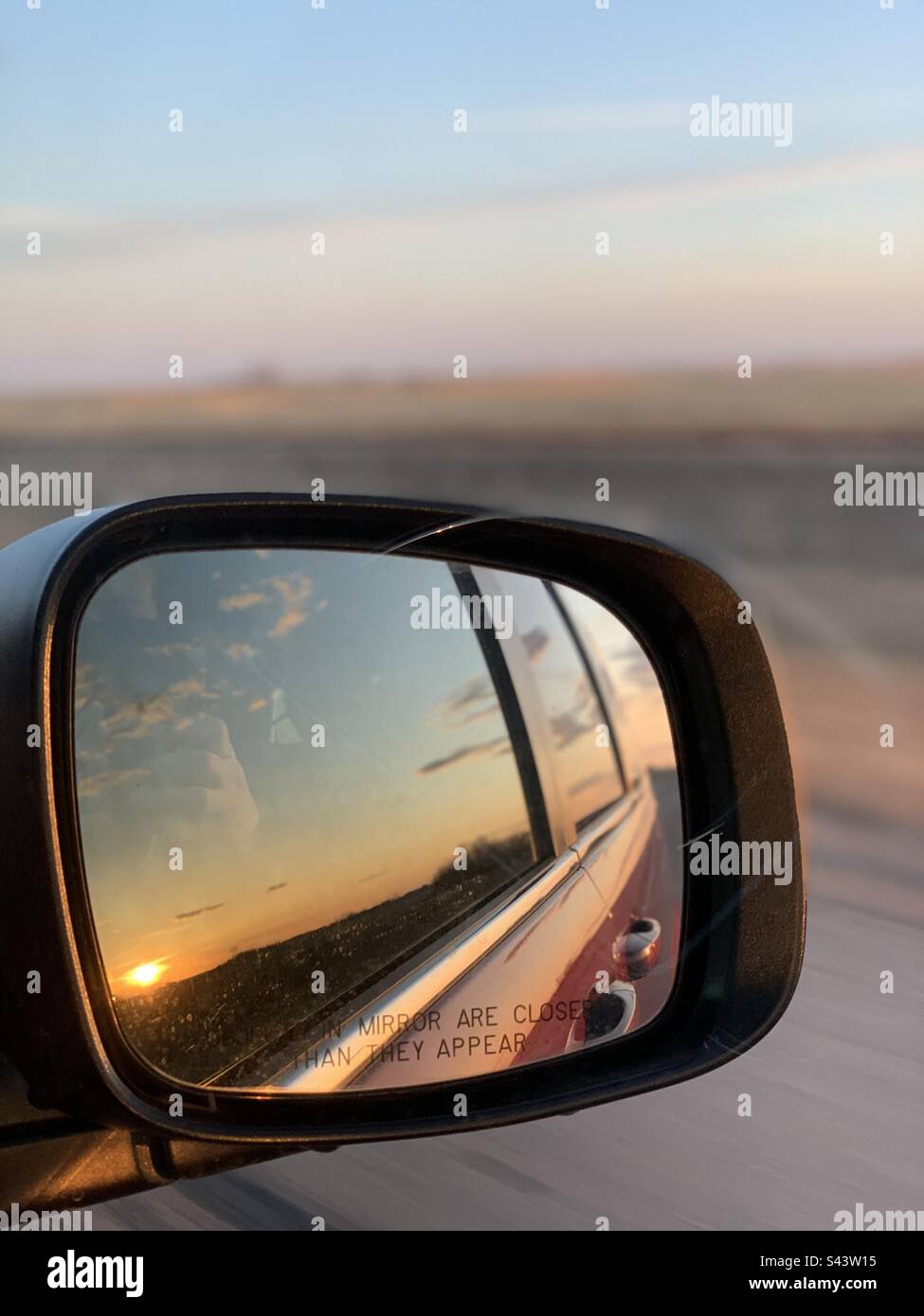 sunset in the sideview mirror with field in the background Stock Photo