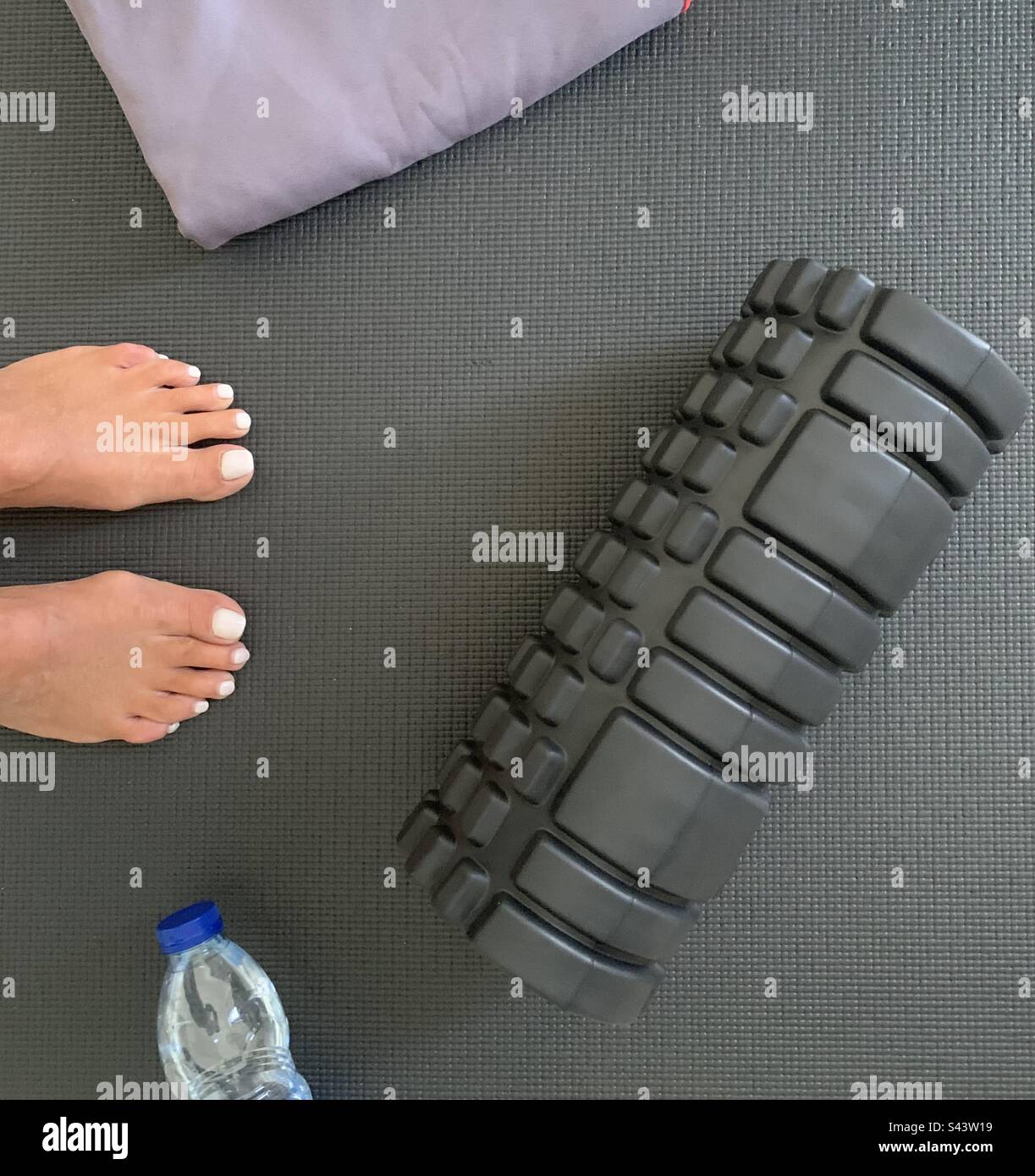 Woman preparing for a morning workout on a gym mat - Smartphone Captured Stock Image