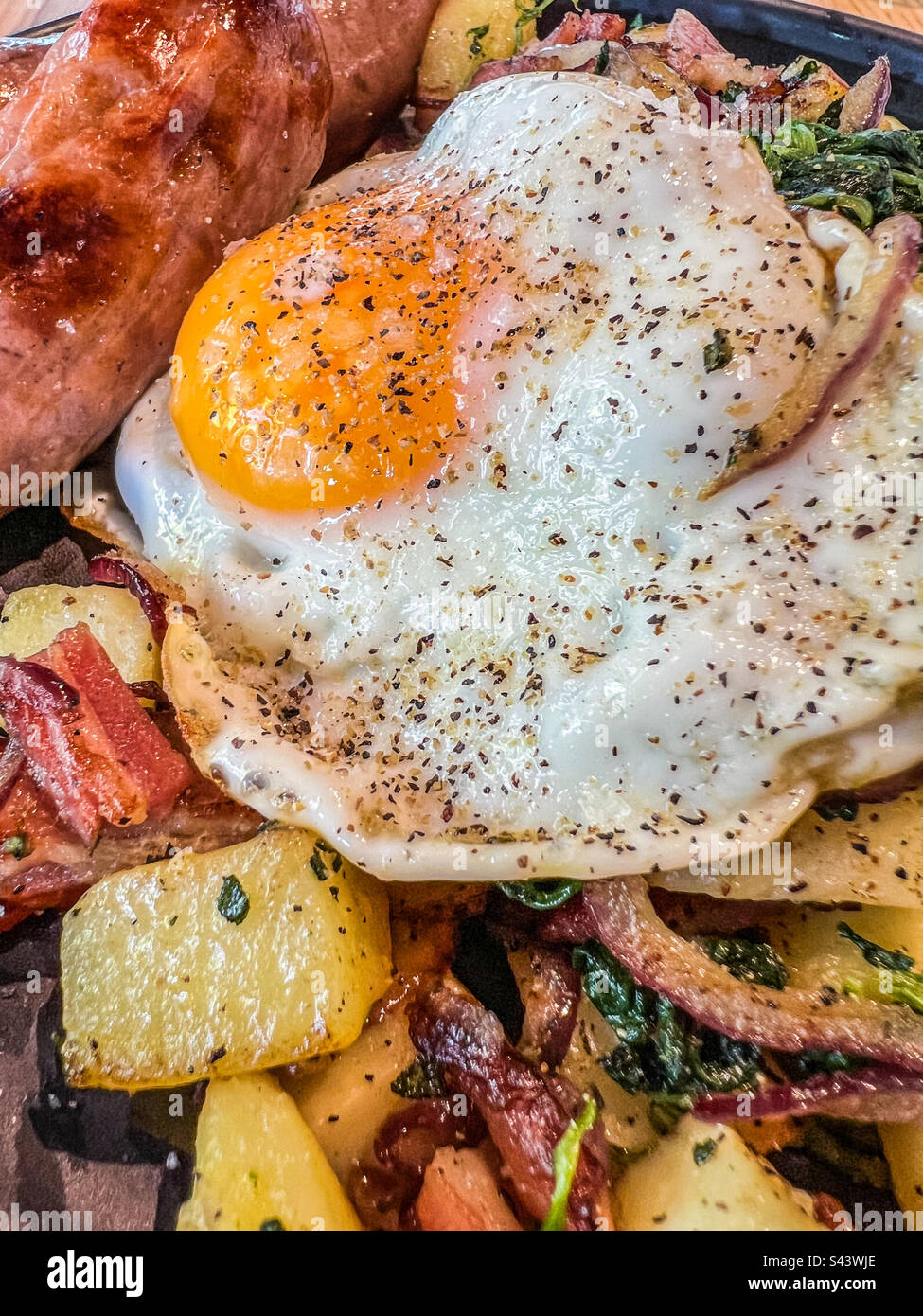 Seasoned fried egg on bacon and potato hash Stock Photo