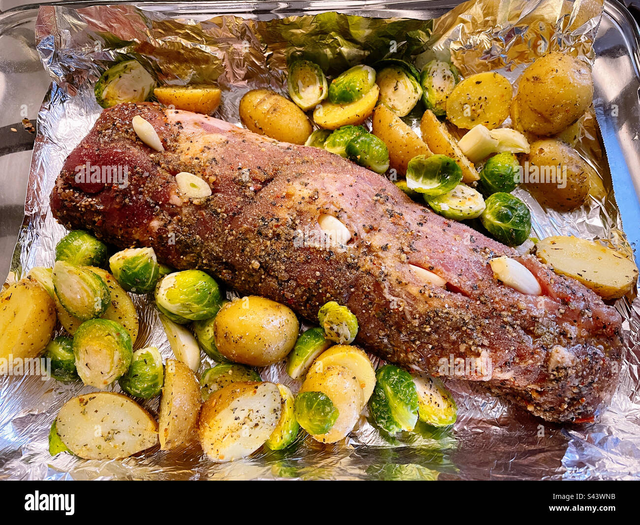 Pork tenderloin roast with broccoli and new potatoes started with garlic cloves, 2023, USA - Smartphone Captured Stock Image