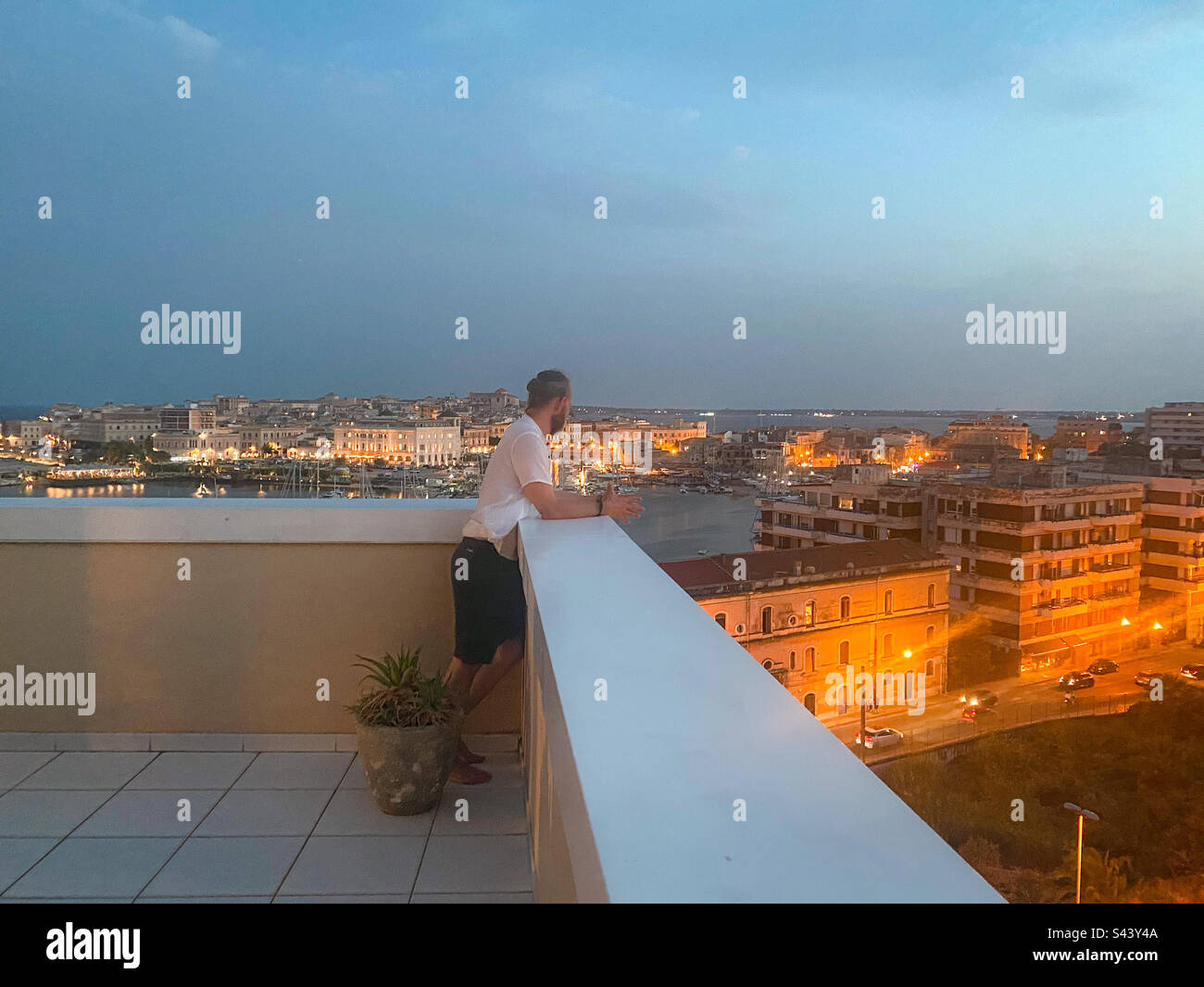 Man in white shirt and shorts enjoying the view. Syracuse, Sicily, Italy. - Smartphone Captured Stock Image