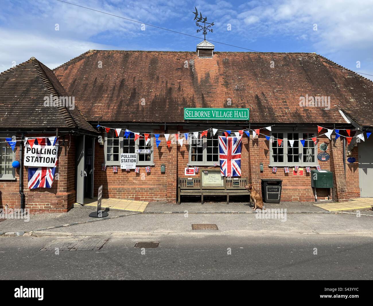 Union flags, bunting and a polling station sign are seen hanging at Sherborne Village Hall in Hampshire on local election day ahead of the Coronation of King Charles III. Stock Photo