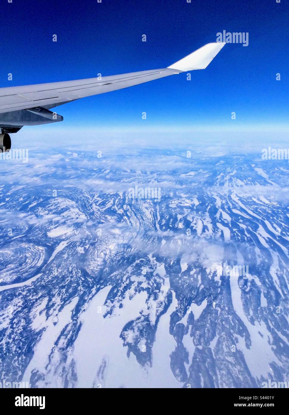 Up in the air: stunning view to the snowy mountains from the airplane window - Smartphone Captured Stock Image