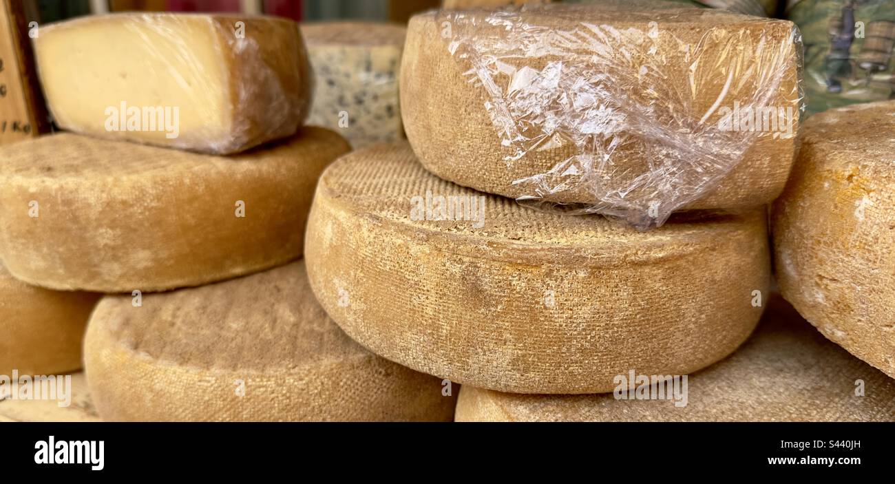 Rounds of cheese, some wrapped in clingfilm on a store in a French ...