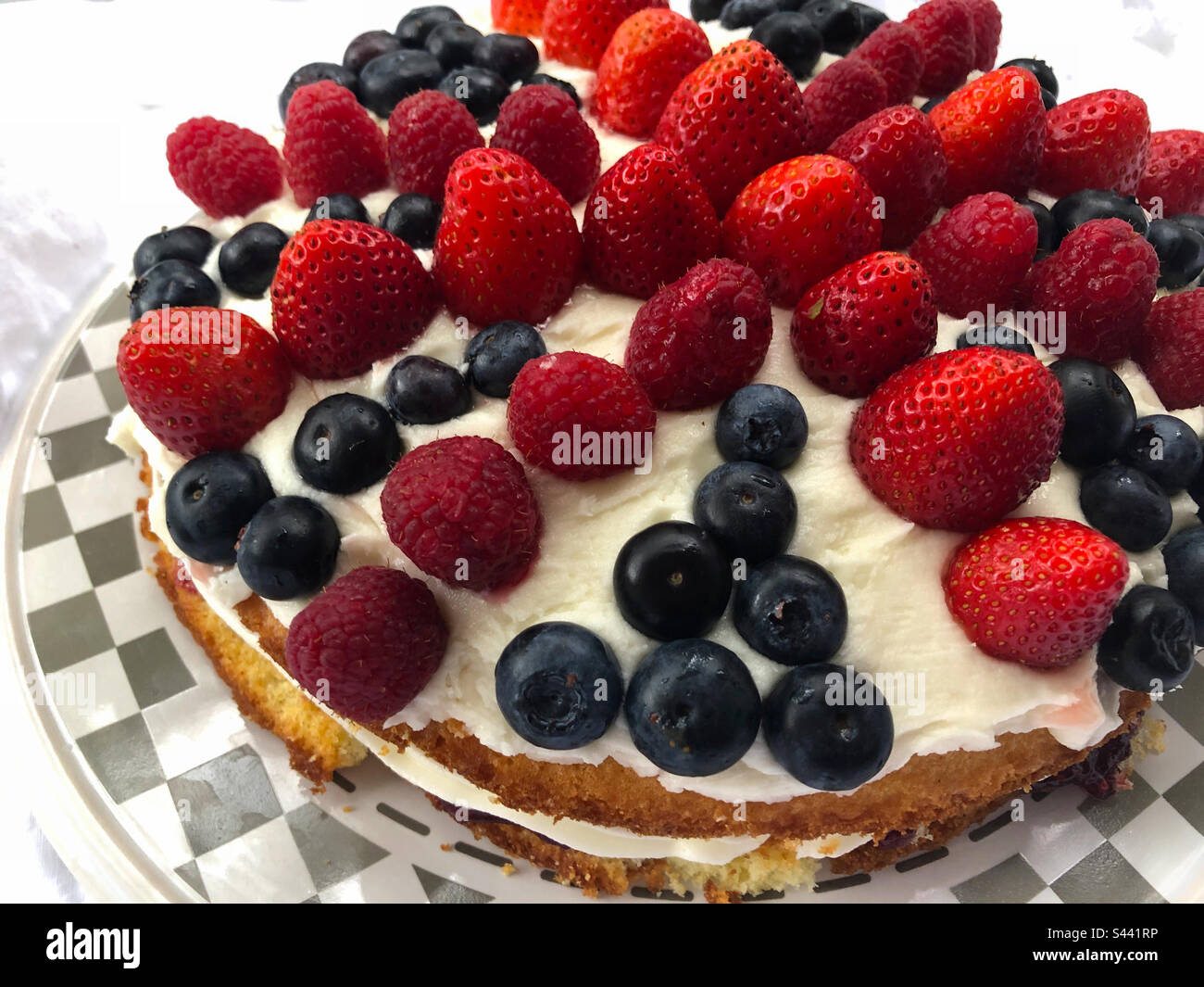 A Victoria sponge with the Union Jack created with berries on buttercream icing. - Smartphone Captured Stock Image