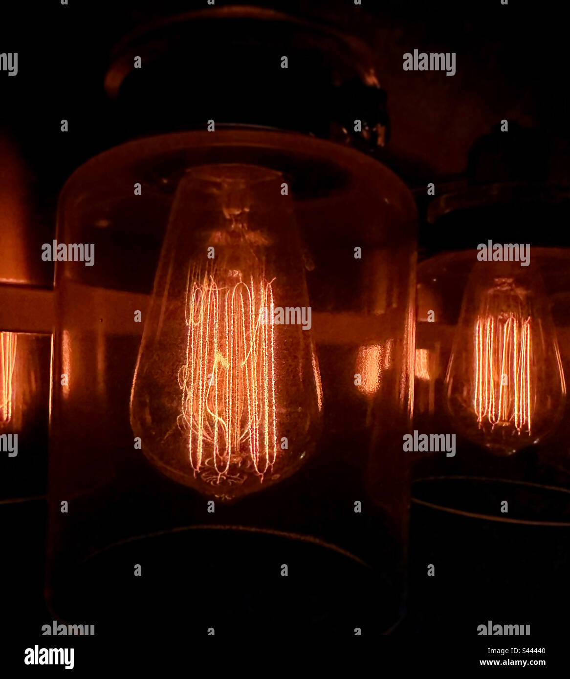 Electric Edison lightbulbs shining in a dark room up close. Stock Photo