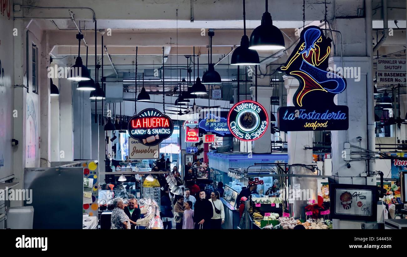 LOS ANGELES, CA, DEC 2022: neon and painted signs hang from the ceiling at Grand Central Market in Downtown. Shoppers and diners below - Smartphone Captured Stock Image