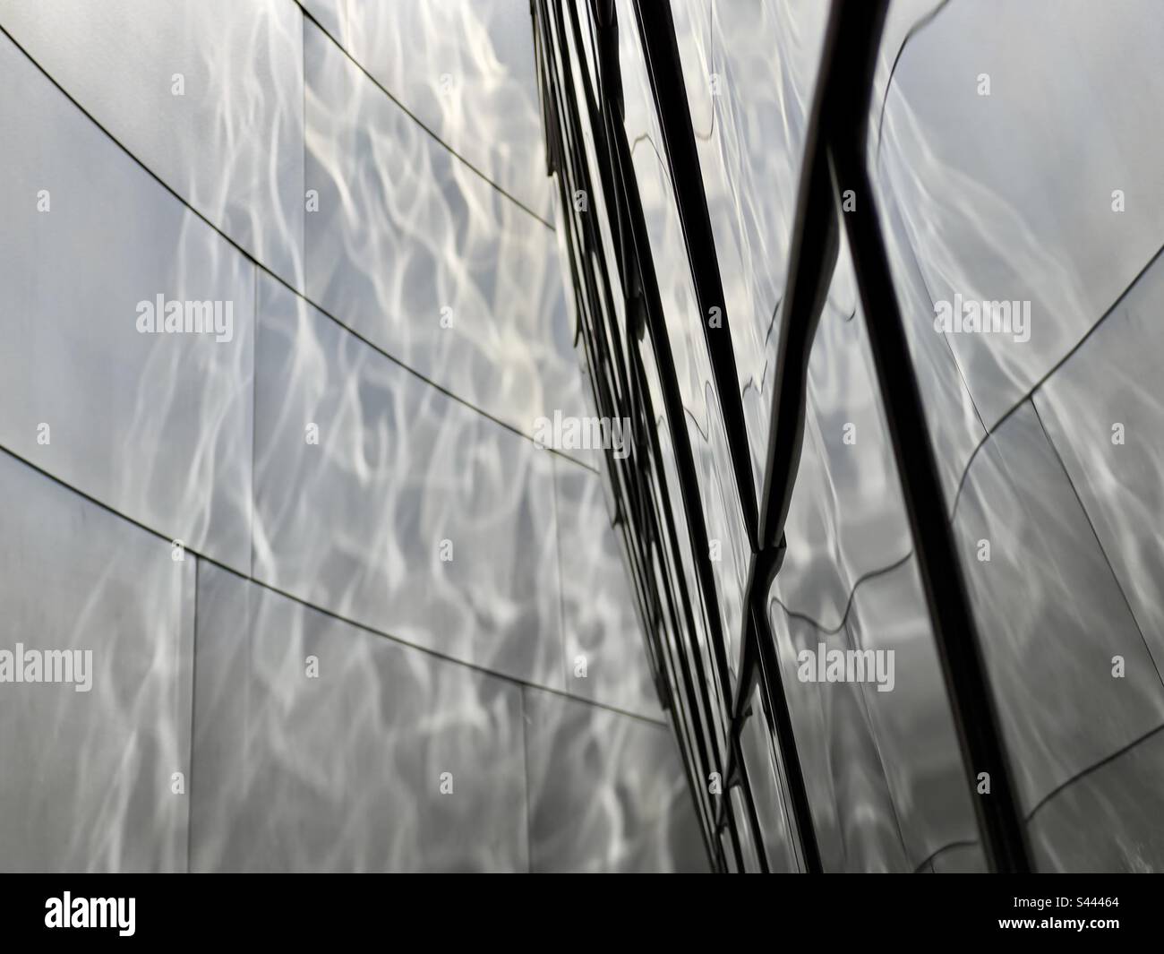 Low sunlight creates rippling reflections on stainless steel wall, with shallow focus on panels in foreground. Abstract texture suitable for graphics backgrounds and wallpapers - Smartphone Captured Stock Image Low sunlight creates rippling reflections on stainless steel wall, with shallow focus on panels in foreground. Abstract texture suitable for graphics backgrounds and wallpapers - Smartphone Captured Stock Image