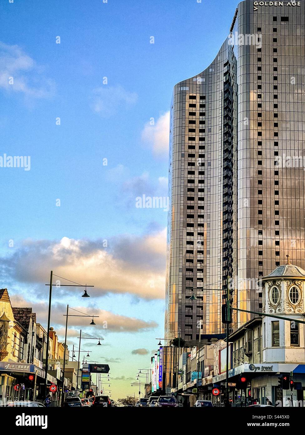 Skyscraper towering over old buildings against blue sky with clouds at sunset in Box Hill, Victoria, Australia. Juxtaposition. Contrast. Old versus new. - Smartphone Captured Stock Image