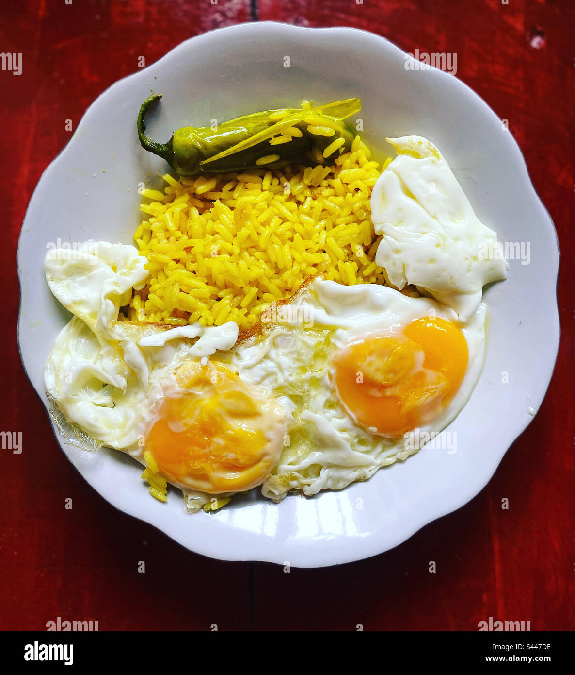 Yellow rice, fried eggs and a green hot serrano chilli pepper in Queretaro, Mexico Stock Photo