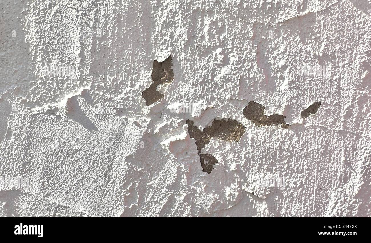 A patch of damaged stucco or plaster sidelit to emphasise the texture and abstract pattern - Smartphone Captured Stock Image