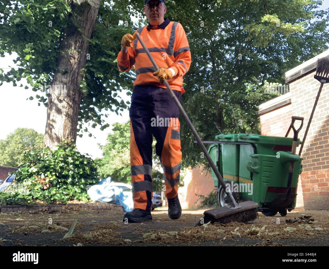 Serco street cleaner in hi vis uniform sweeping Stock Photo Alamy