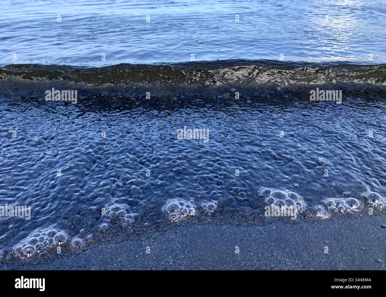 Bubbles in the surf water as a small wave comes in - Smartphone Captured Stock Image