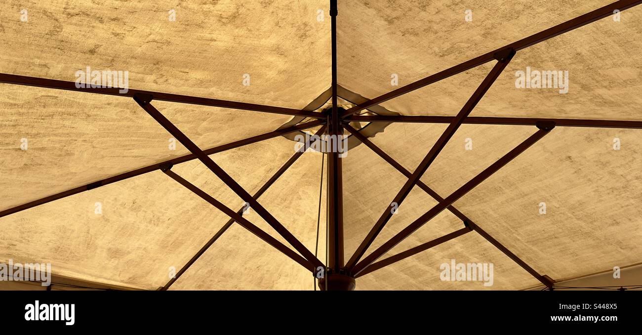 The spokes of a large umbrella or parasol in the garden of a French hotel - Smartphone Captured Stock Image