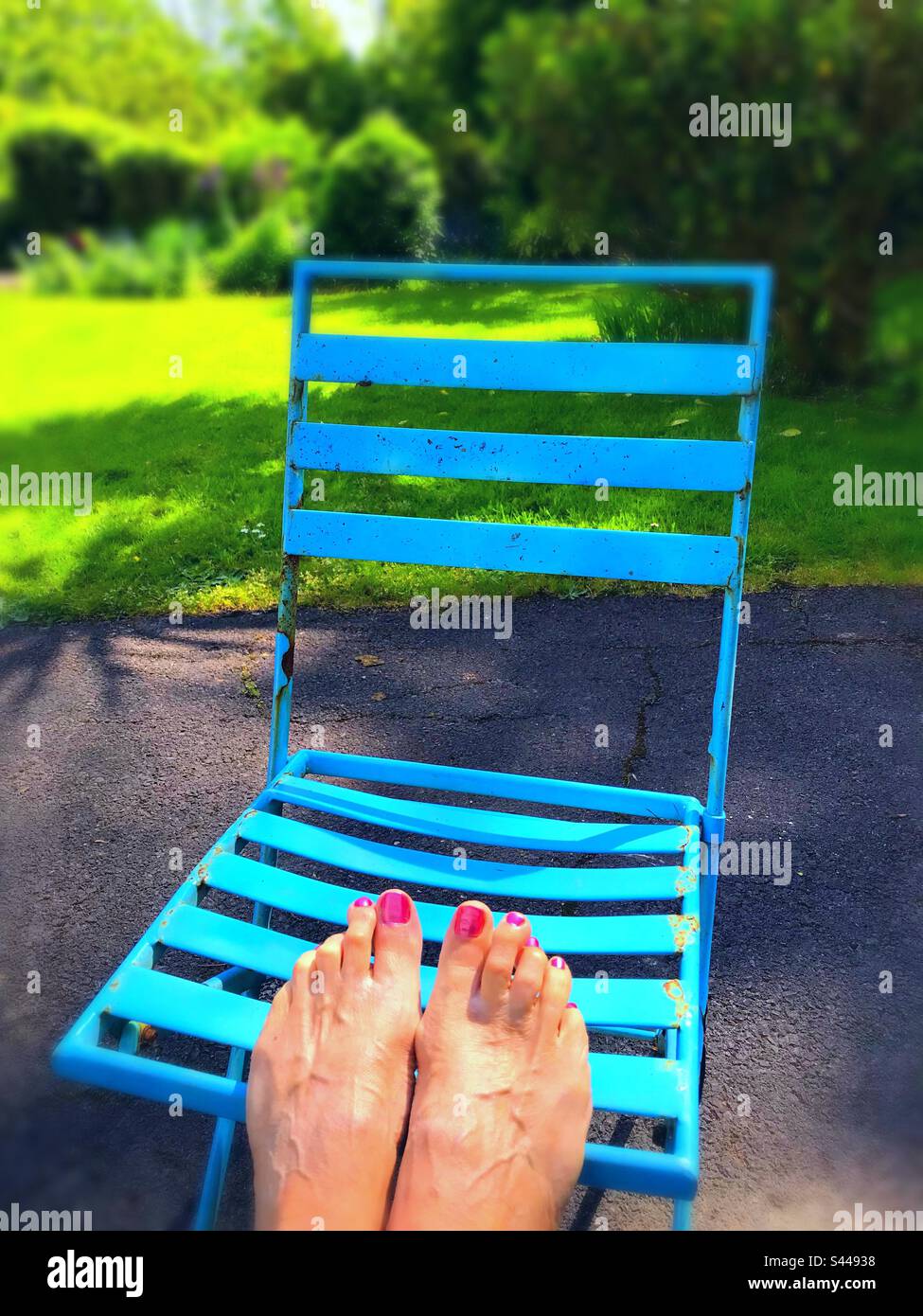 Drying newly painted nail varnish with feet up on chair in the sunshine