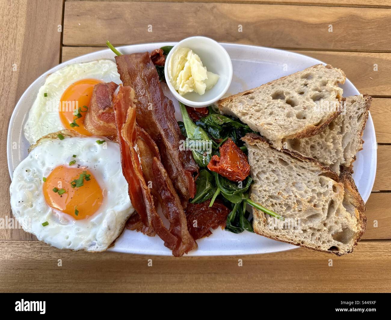 Cooked breakfast of lightly toasted brown bread, spinach, fried eggs and bacon - Smartphone Captured Stock Image