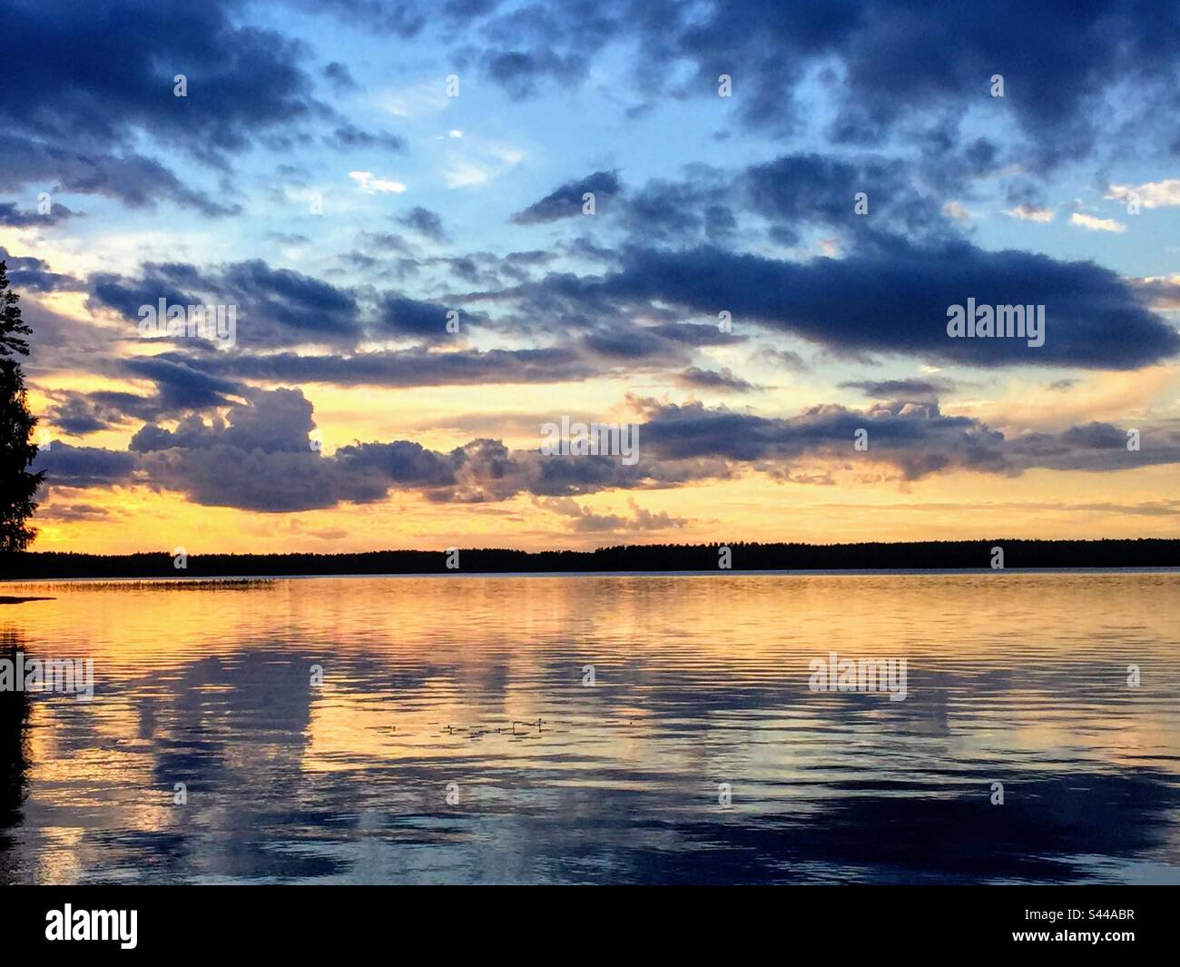 Stunning magic dramatic sunset over the smooth sea water surface with the multiple clouds layers reflection Stock Photo