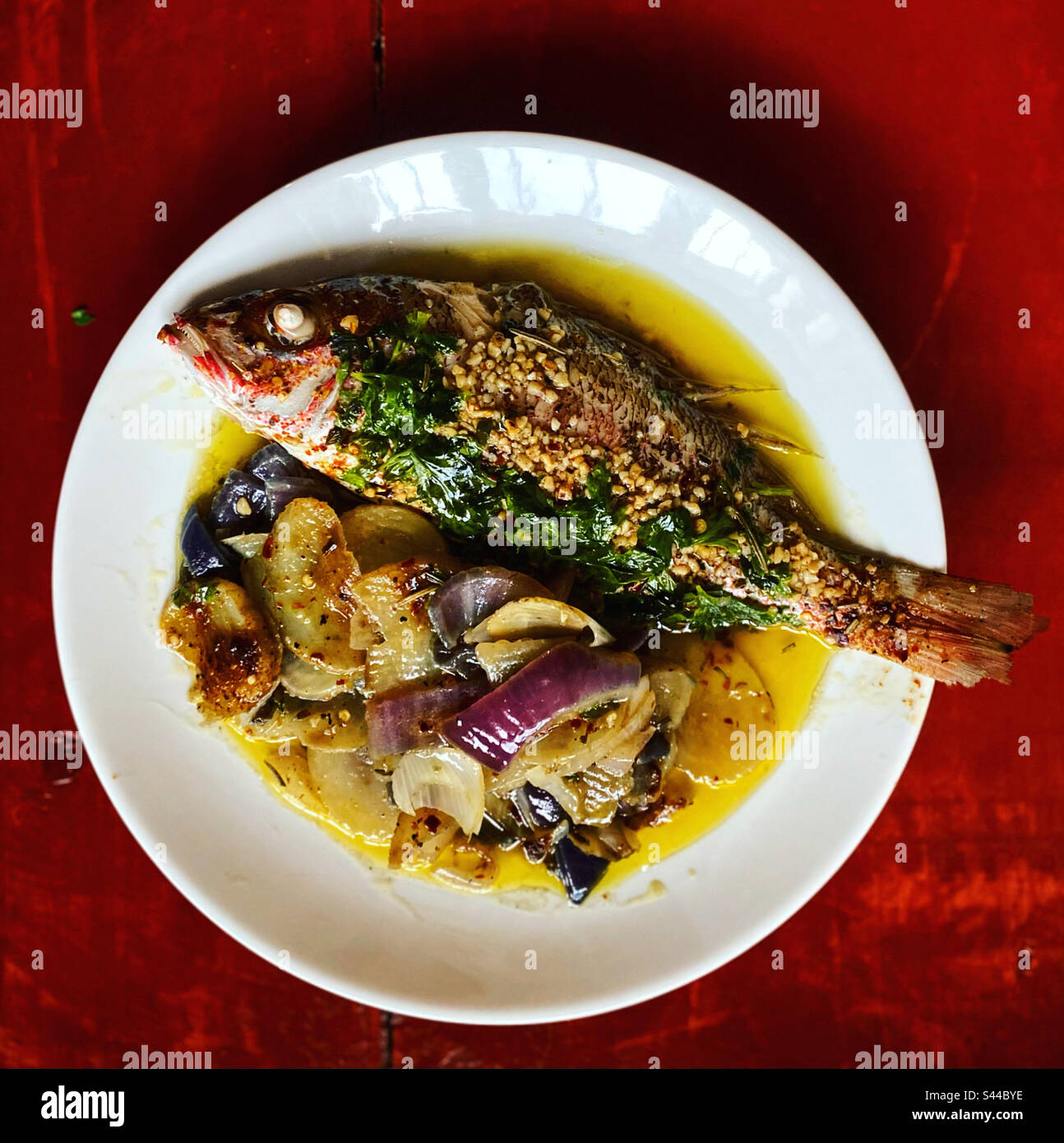A red snapper with herbs with potatoes and red onion in Queretaro, Mexico - Smartphone Captured Stock Image
