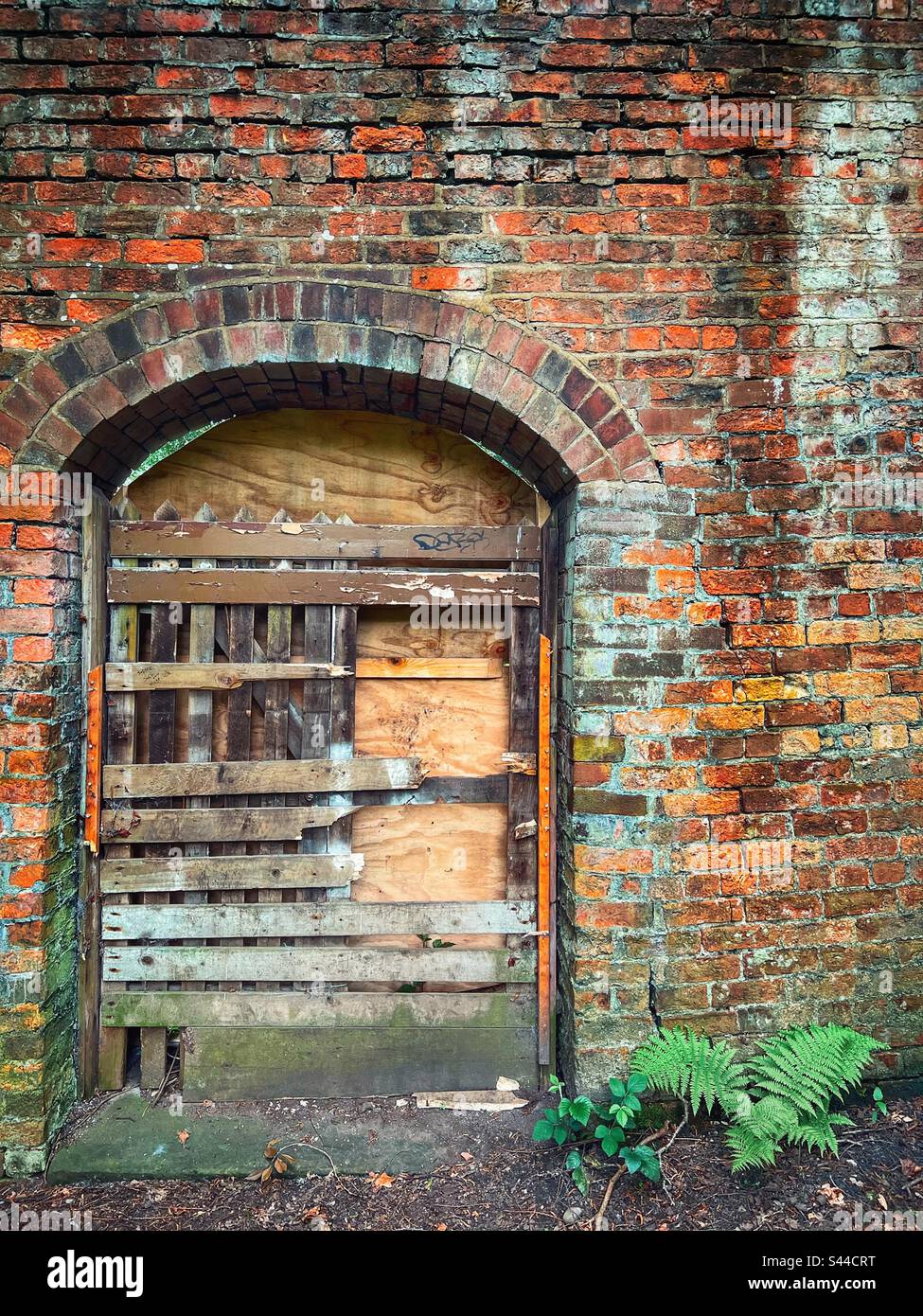 Old boarded up door in cracked brick wall at Witton Park in Blackburn - Smartphone Captured Stock Image