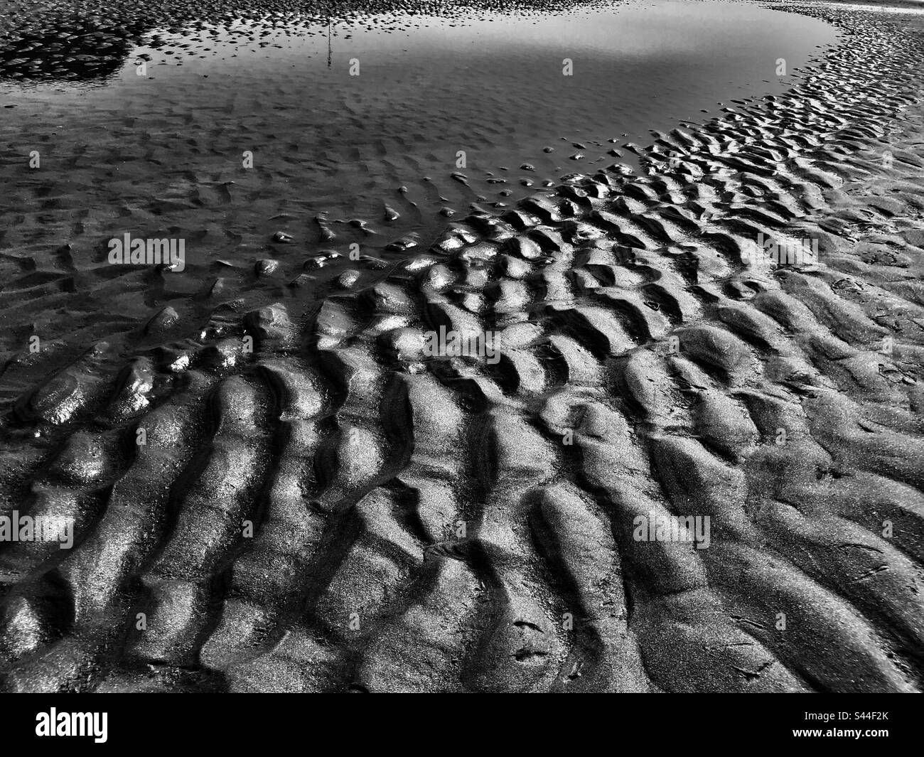 Pattern in the wet beach sand made by ocean water and waves, - Smartphone Captured Stock Image