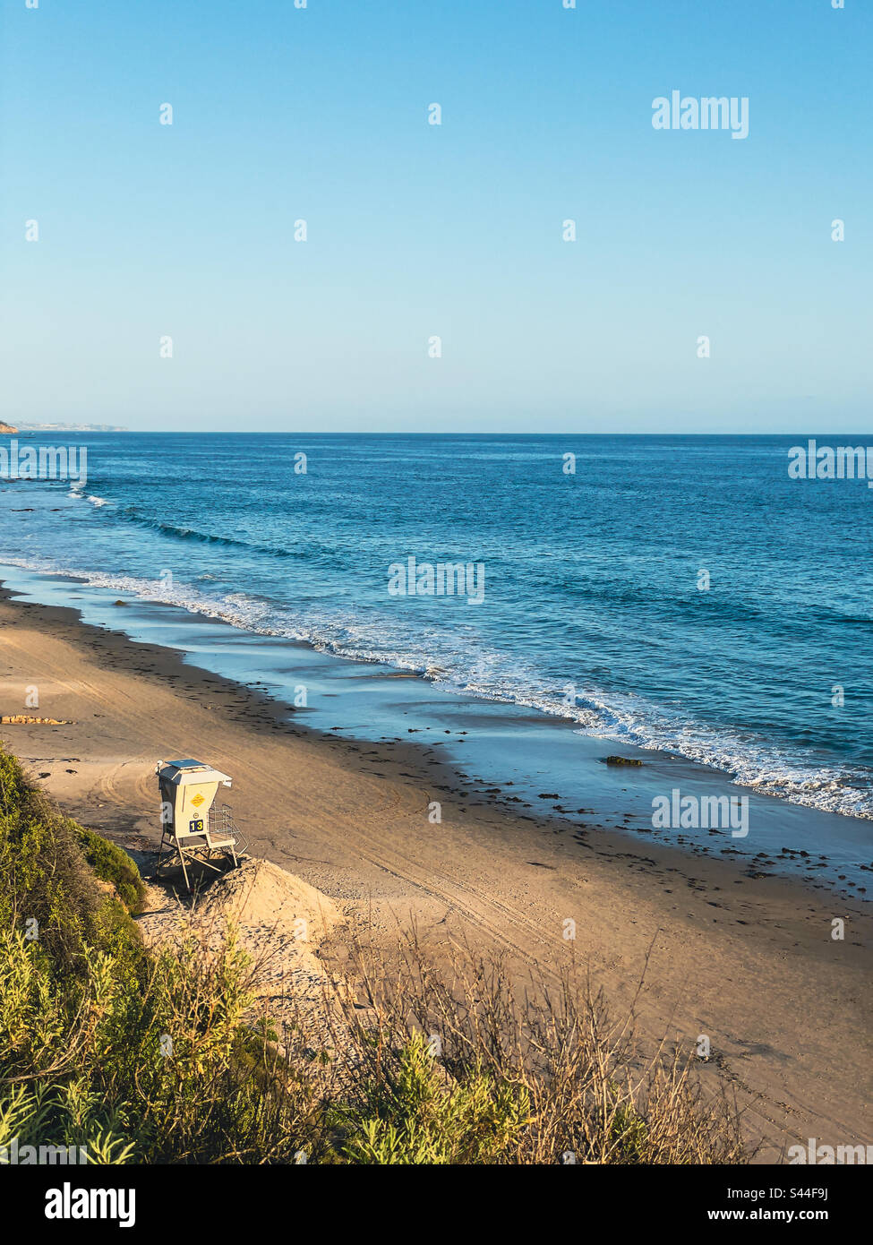 High angle view of a sandy beach with lifeguard stand and ocean under a blue sky. Stock Photo