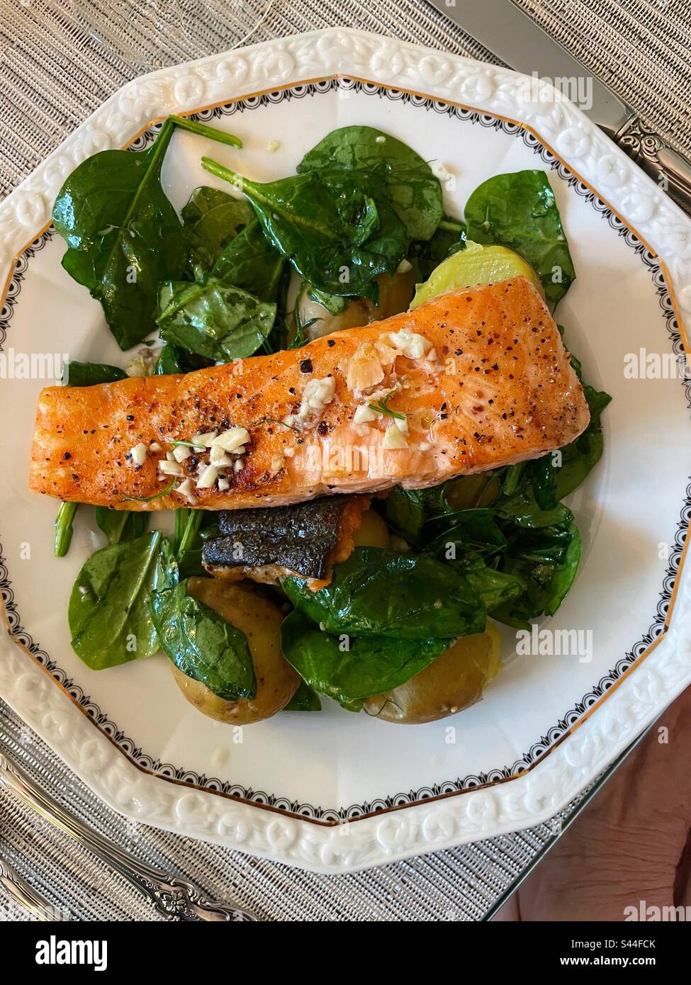 Flat lay of a fillet of salmon on a bed of spinach and new potatoes on a fine china plate, 2023, USA - Smartphone Captured Stock Image