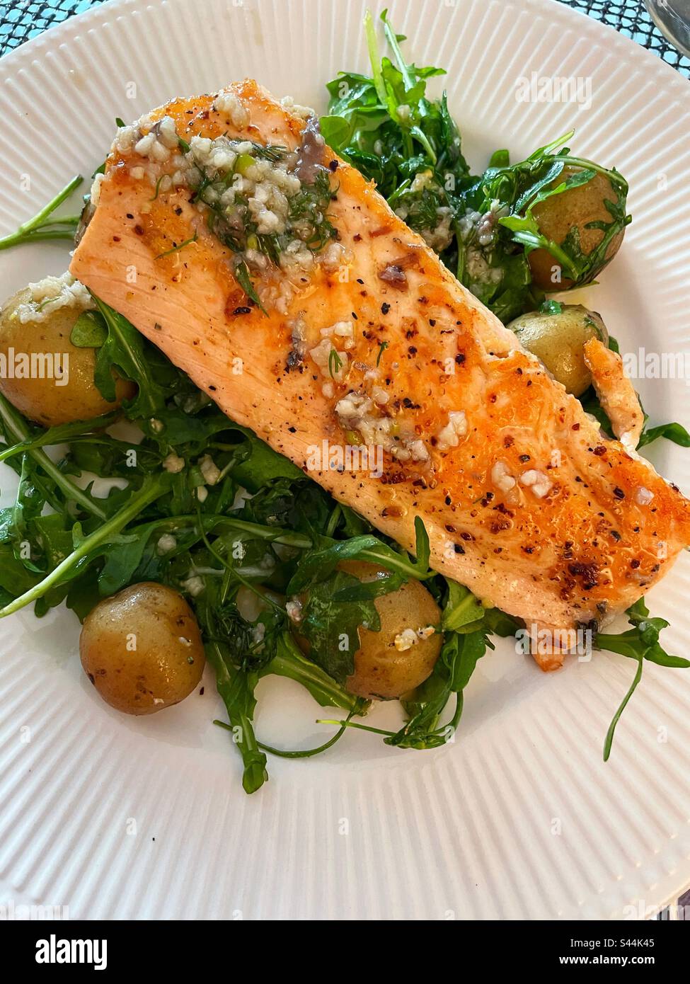 Close-up of a gourmet entrée of broiled salmon fillet with a lemon garlic sauce on a bed of arugula and new potatoes, 2023, USA - Smartphone Captured Stock Image
