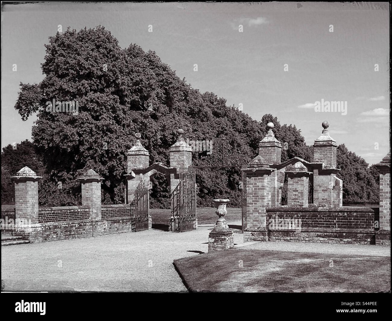 View of the iron gateway with brick pillars at an English countryside Manor House. A retro effect has been added to simulate the effect of an early 20th Century picture. Photo ©️ COLIN HOSKINS. - Smartphone Captured Stock Image