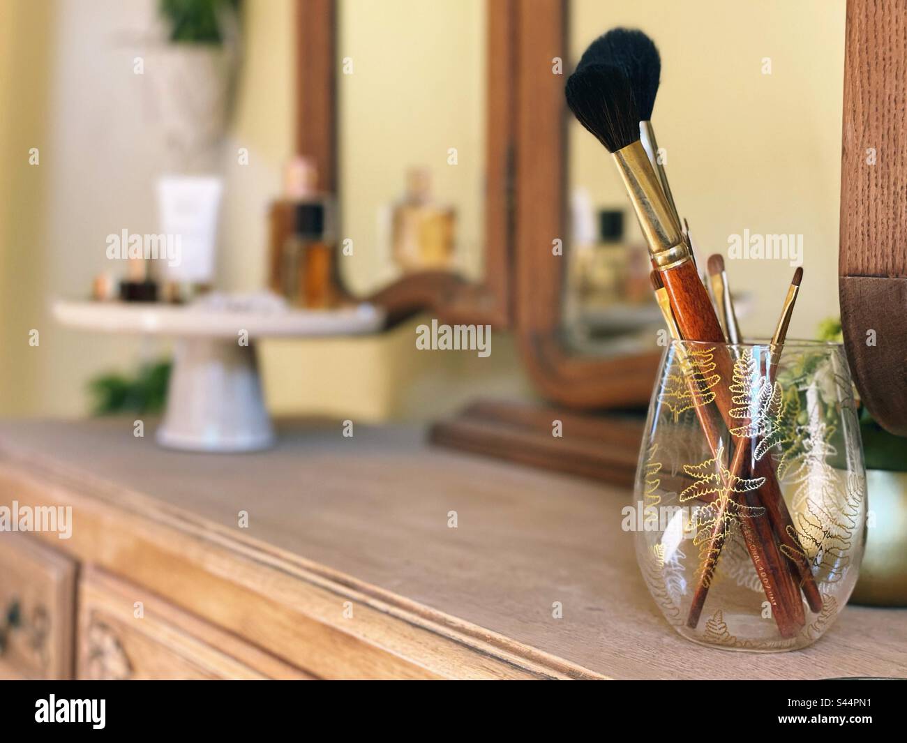 Makeup brushes in a glass on a vanity table Stock Photo