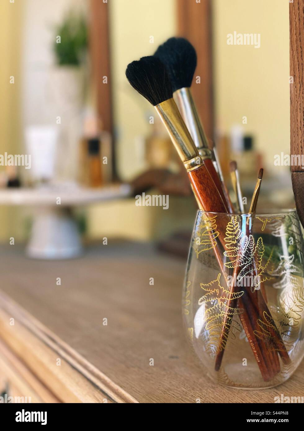 Vanity table with makeup brushes in a glass Stock Photo