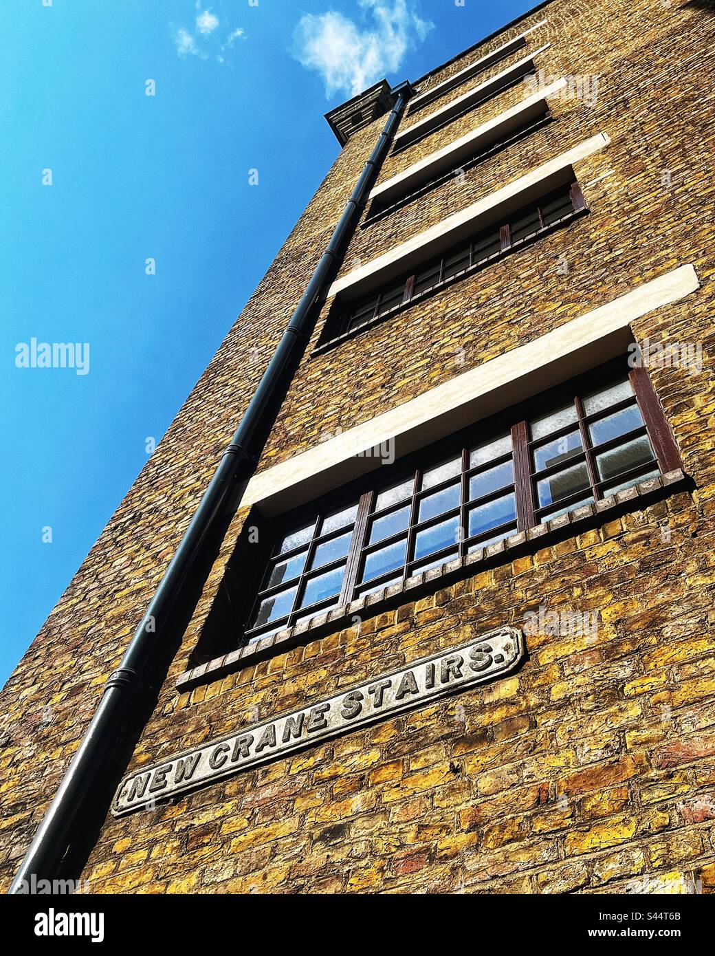 New Crane Stairs has existed since before 1746 as it appears on a map dated from then. The street sign in Wapping E1 is on a wharf building on the banks of the river Thames in London - Smartphone Captured Stock Image