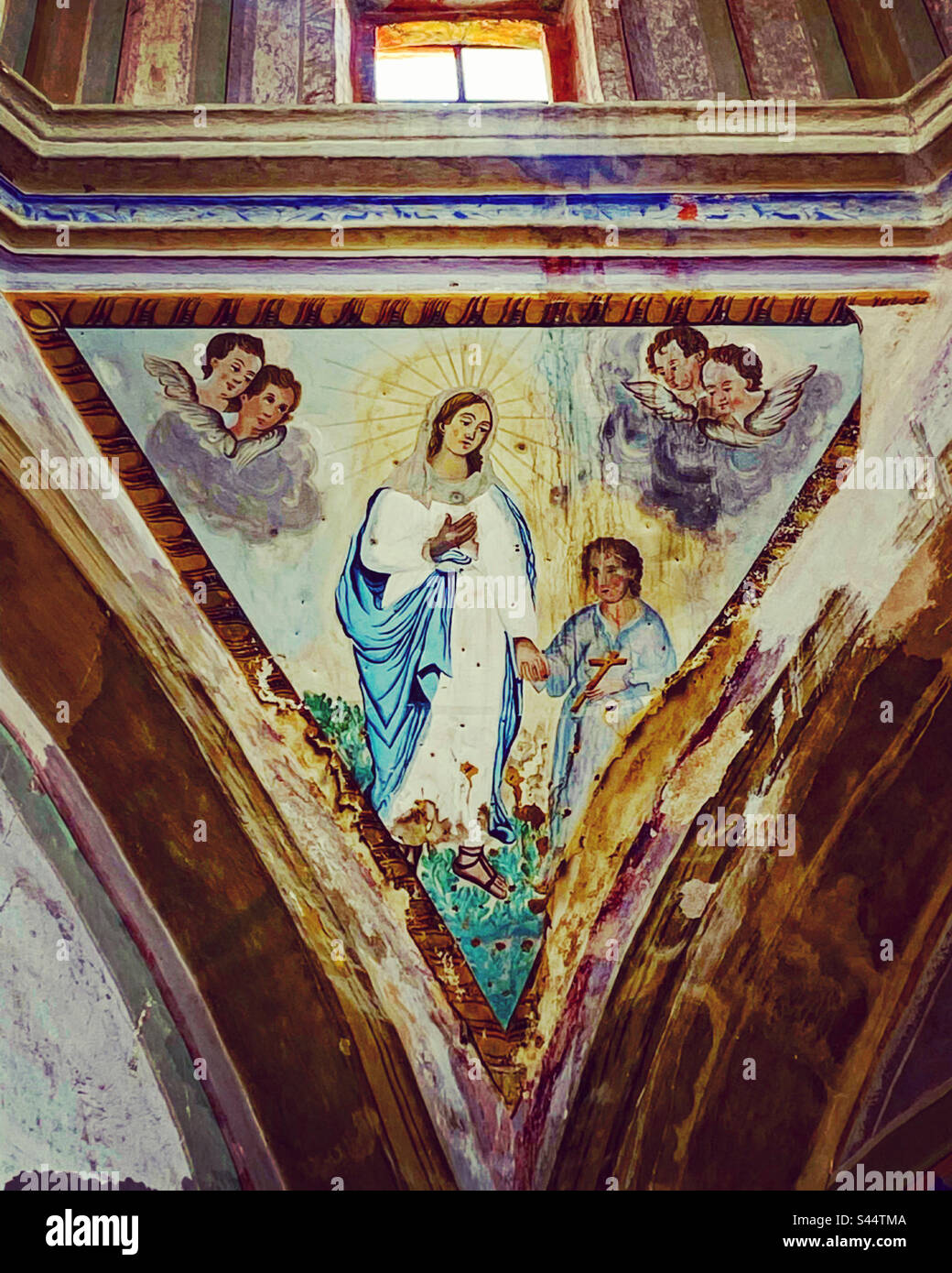 An old painting of the Virgin Mary holding a Baby Jesus Christ by the hand an escorted by cherubs decorate Nuestra Señora de los Dolores in Toliman, Queretaro, Mexico - Smartphone Captured Stock Image