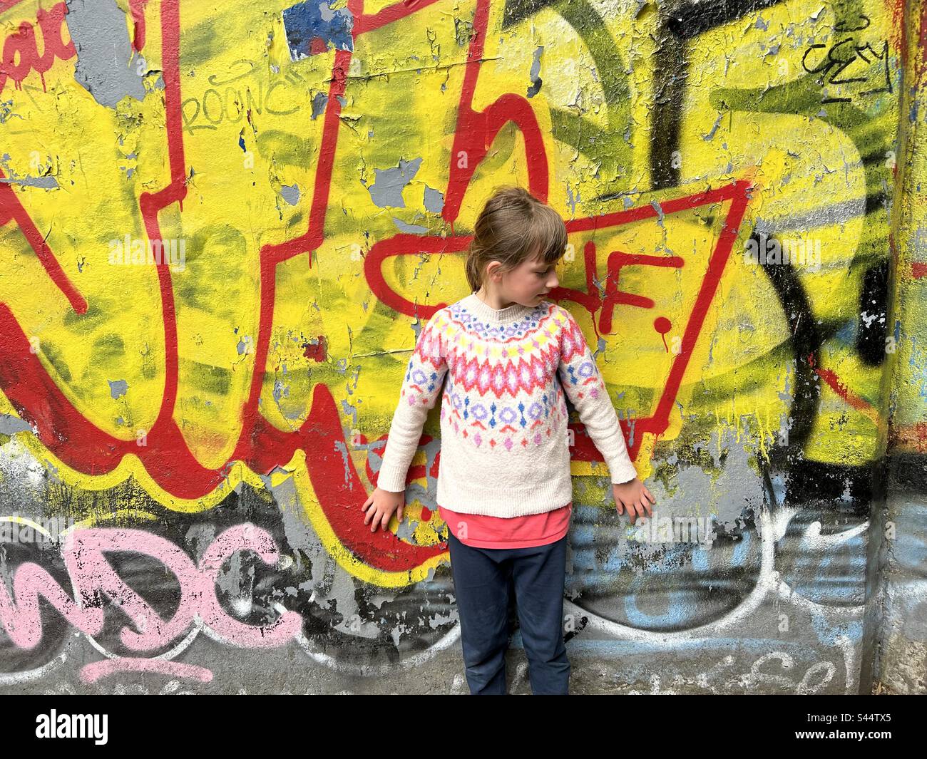 Graffiti wall along the Ouseburn, Newcastle. A girl leans against it - Smartphone Captured Stock Image