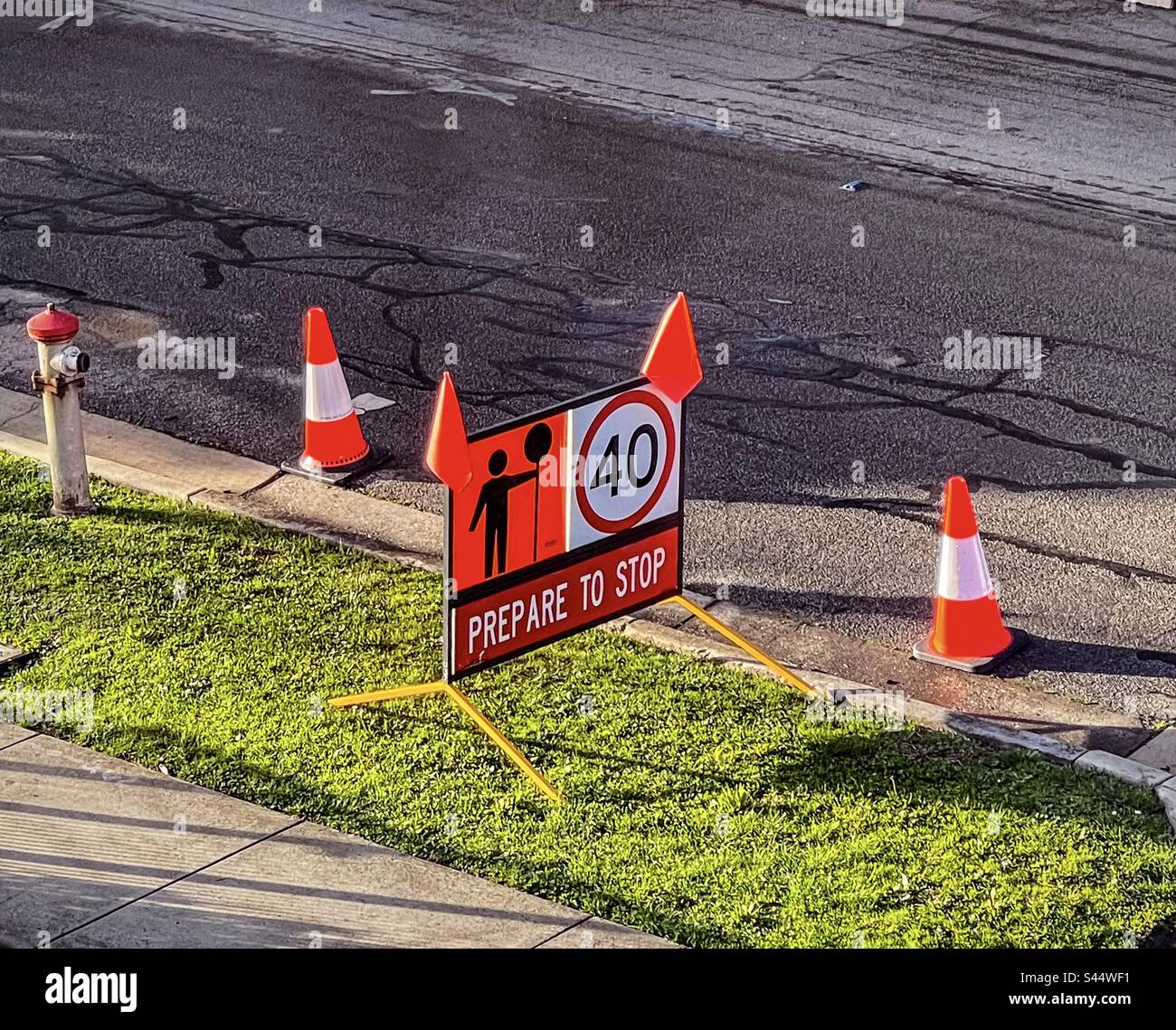 Traffic cones and warning sign on nature strip beside road indicating road works ahead and speed limit of 40 km/hr. Stock Photo