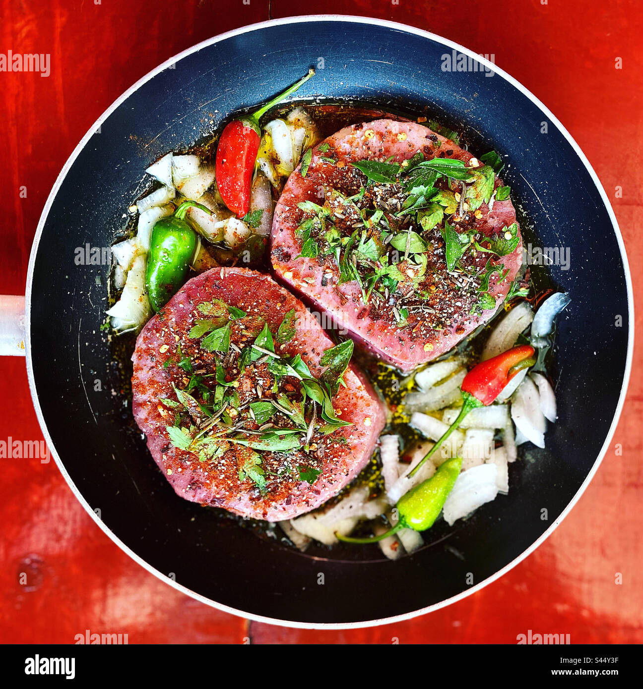 Two tuna fish medallions covered with fine  herbs and red and green chilli peppers with onion ready to be grilled in Queretaro, Mexico Stock Photo