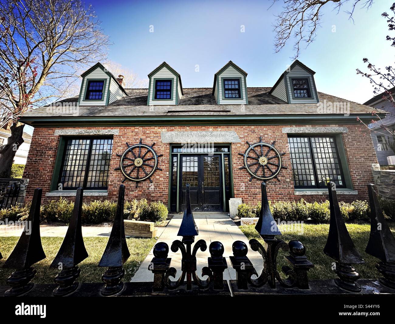 Pratt’s Village Smith building in Essex, Connecticut, USA. View of red brick structure from black fence. Historical architecture. - Smartphone Captured Stock Image