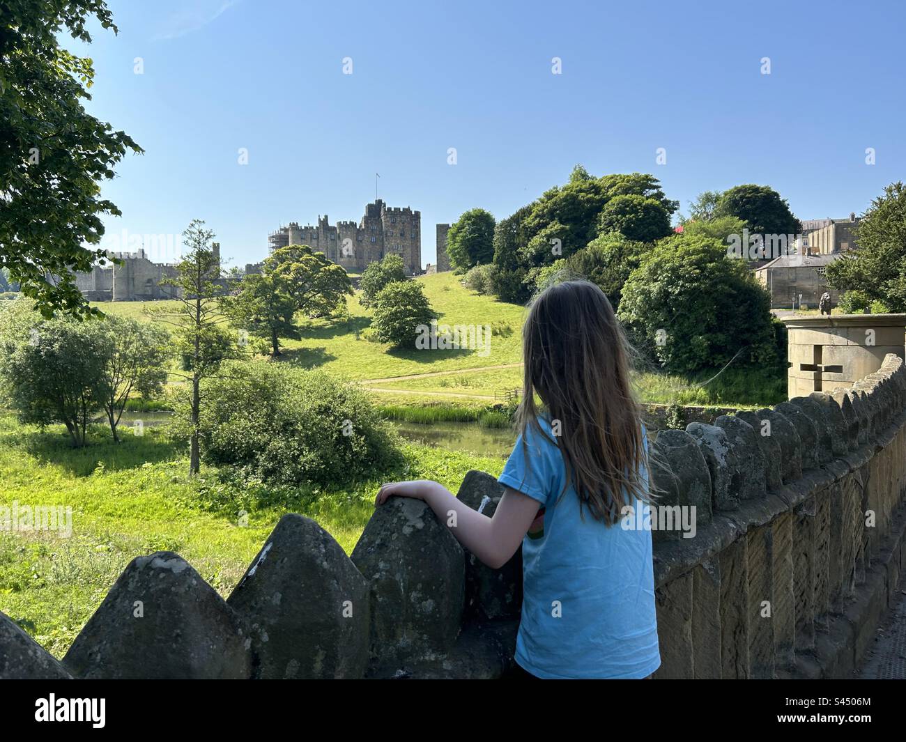 8 year old girl looking out over the bridge to Alnwick castle in Northumberland Uk - Smartphone Captured Stock Image