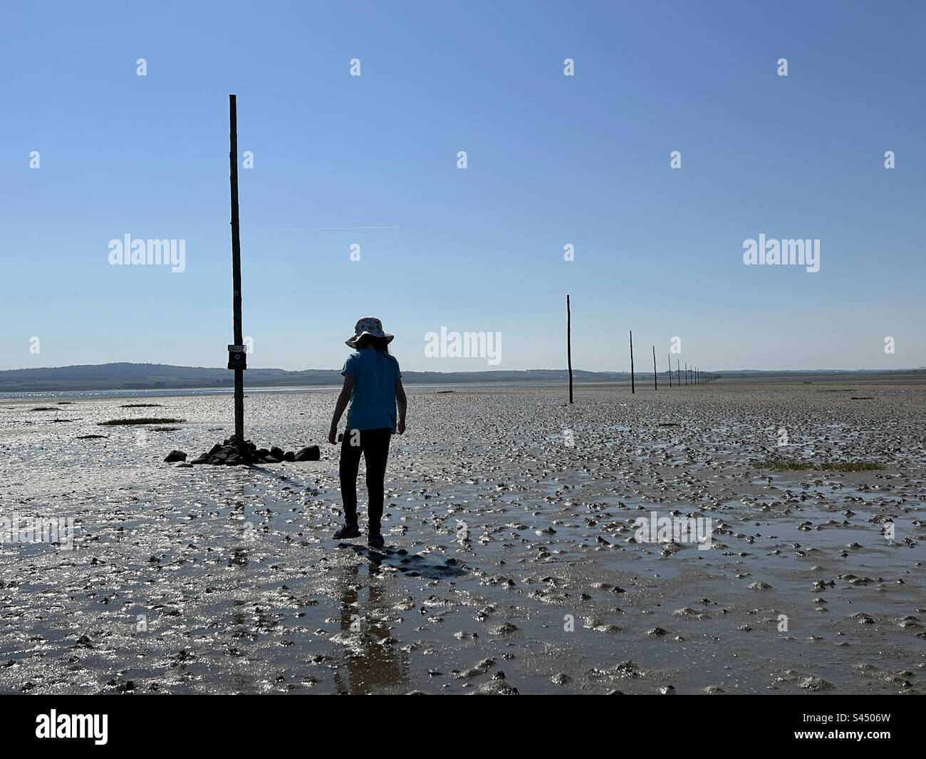 Girl walking across Holy Island Sands to Lindisfarne in Northumberland. Britain - Smartphone Captured Stock Image