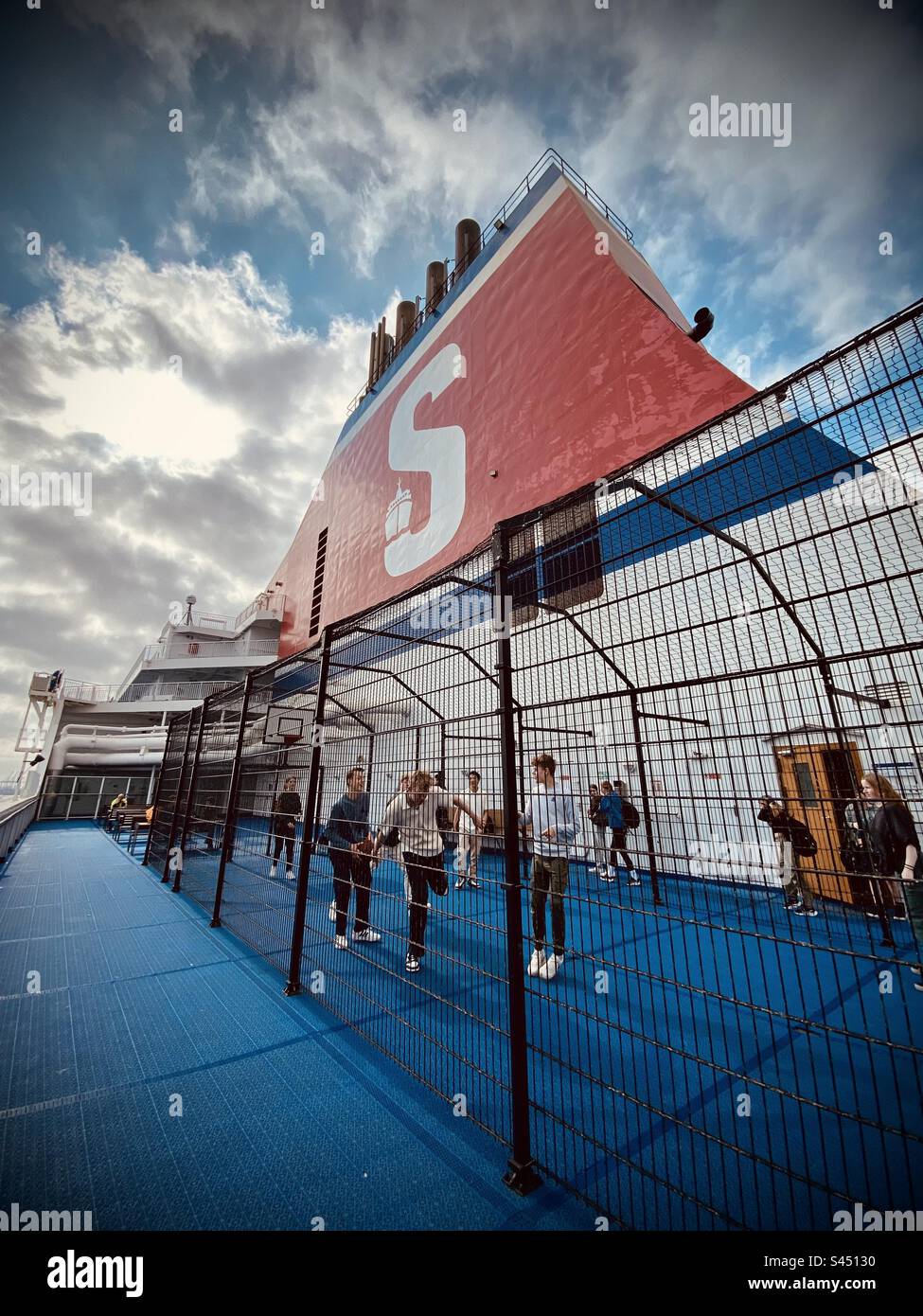 Kids playing basketball in a cage on a ferry across the English Channel - Smartphone Captured Stock Image