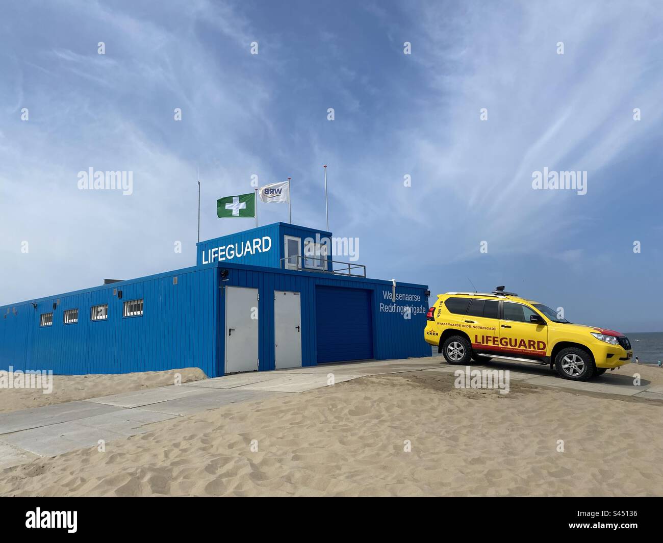 A yellow lifeguard vehicle and blue building on the coast in Holland - Smartphone Captured Stock Image