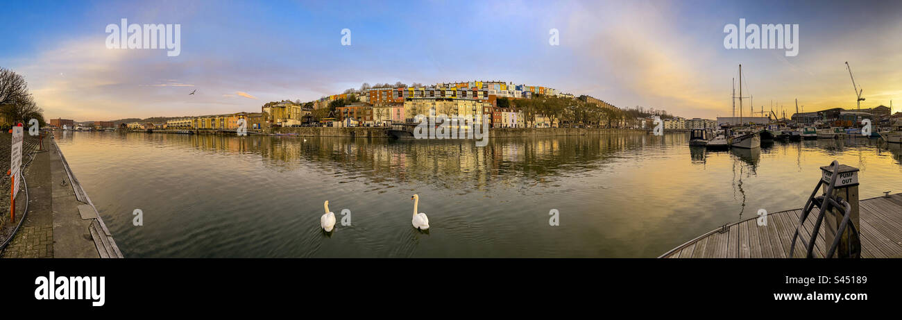 Panoramic view of the Grain Barge floating bar and restaurant with rows of colourful houses behind, seen from the marina looking North at sunrise. UK - Smartphone Captured Stock Image