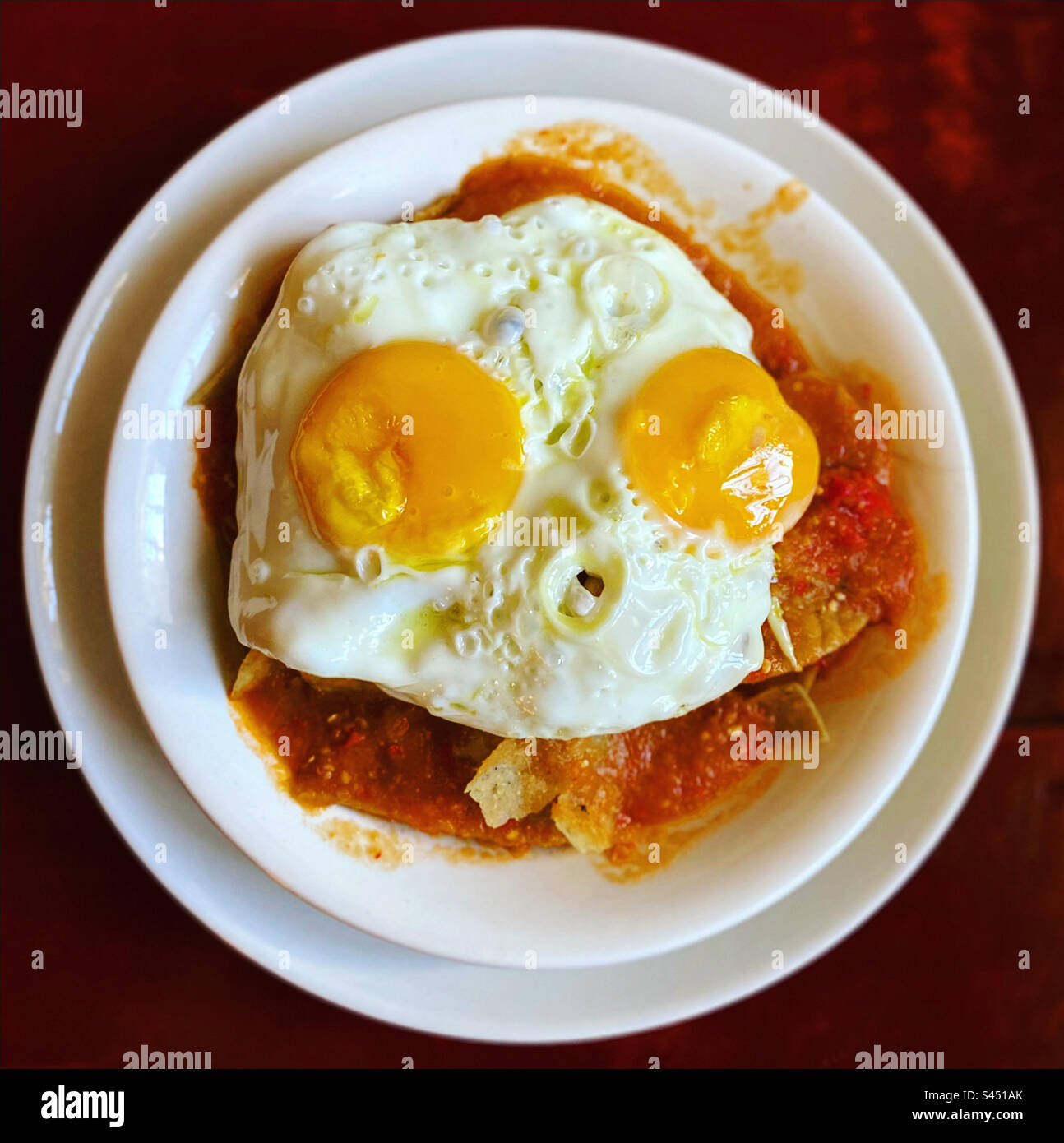 Red corn chilaquiles with two eggs in Queretaro, Mexico Stock Photo